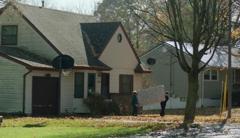 A woman and her teenage son carry a mattress out of their home and put it on the curb