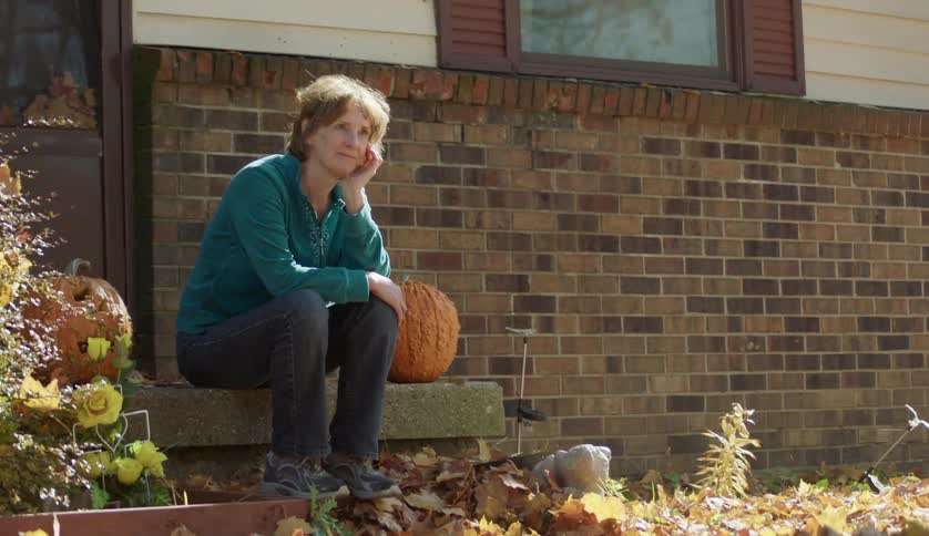 Contemplating woman sitting on porch step in the fall