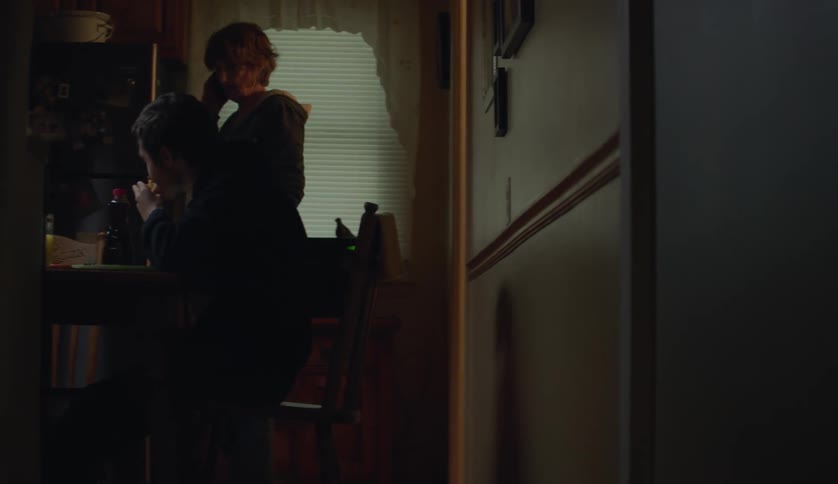 Woman talking on the phone enters the kitchen where her grandson is eating