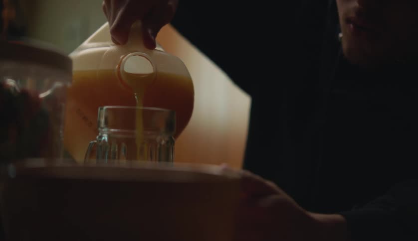 A male is pouring himself some orange juice