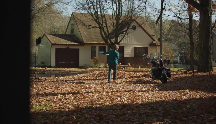 Woman carries a cardboard box into her house at fall