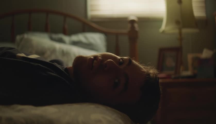 Man lying on bed talks to person in his room