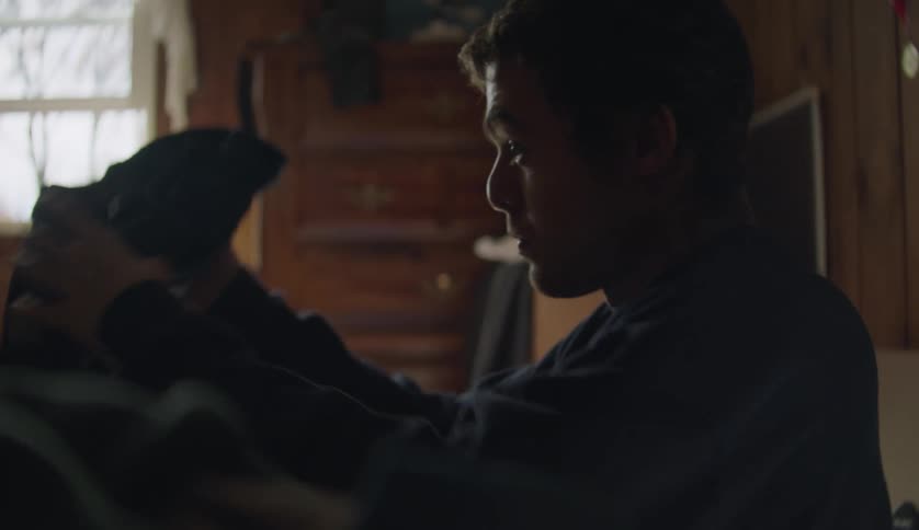 Man with dark blue sweater folds clothes in room