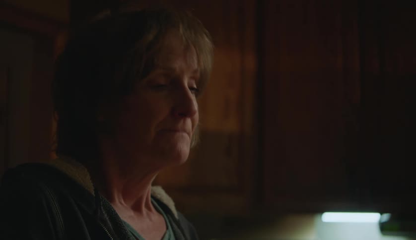 A woman is nodding her head while talking to someone else in a kitchen