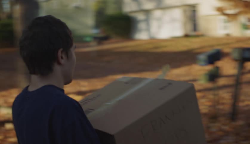 Two people are moving boxes out of a house