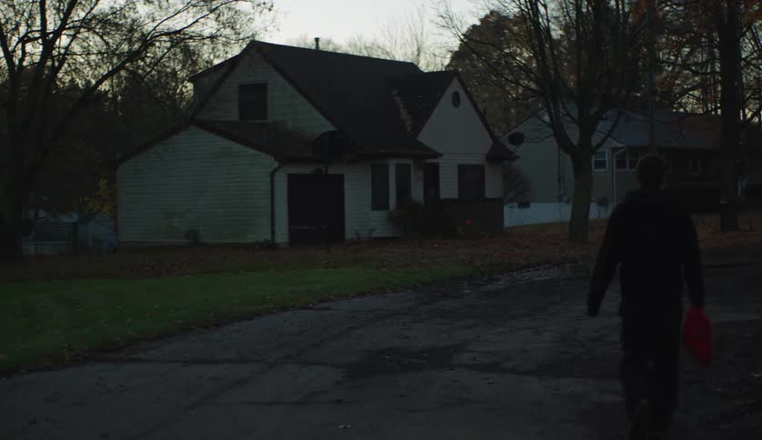 Silhouette of a young man walking on the street of a neighborhood at evening