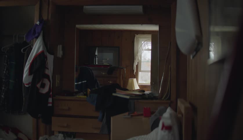 A male is putting away clothes in his room
