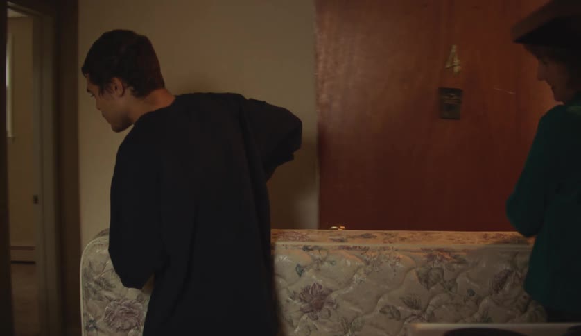 Male and female moving a mattress into an apartment