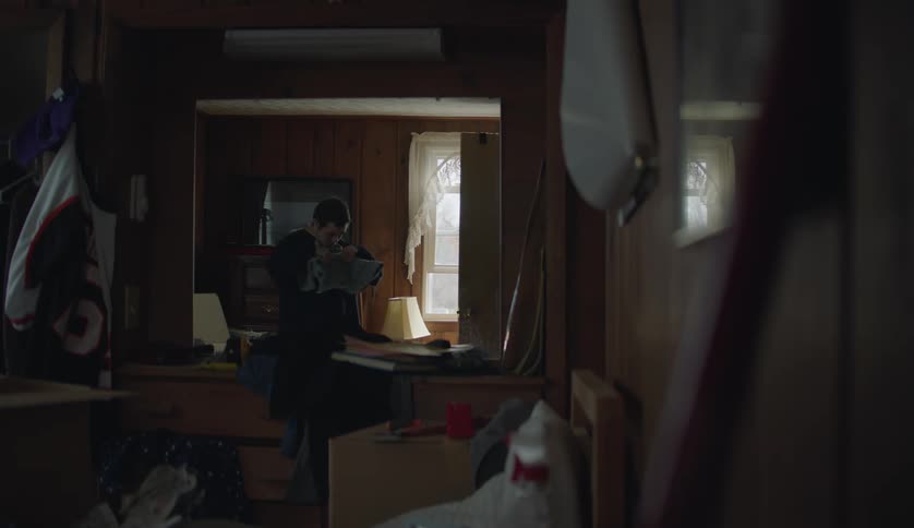 A young white man is indoors and going through some of his belongings