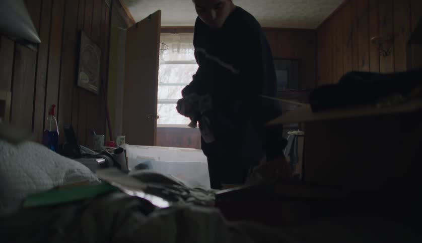 A young white man is cleaning up his bedroom