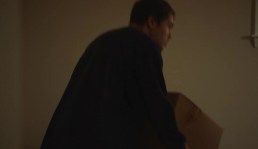 A teenage boy and his mother are moving boxes in a room