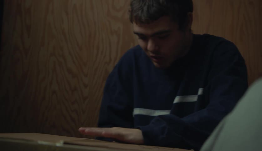 A young white man is inside and taping up a box