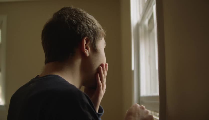 A young man is inside of his house in the middle of the day