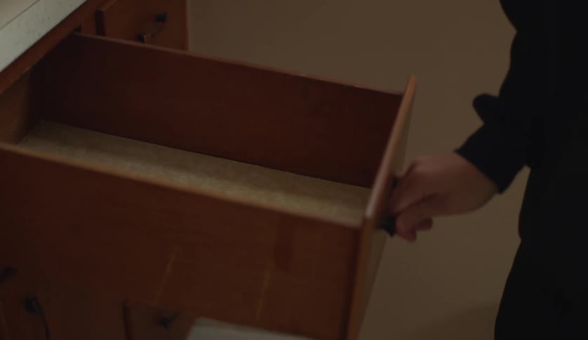 Someone is standing near the kitchen sink and they open an empty drawer