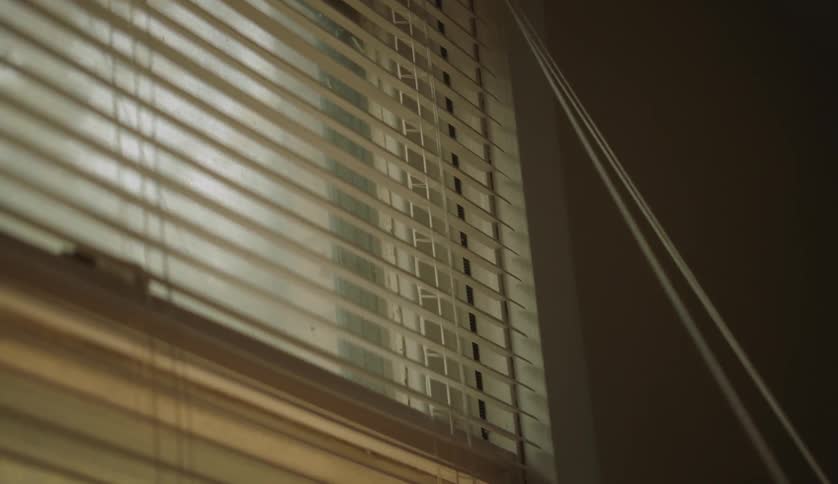 Person opens window blinds in room