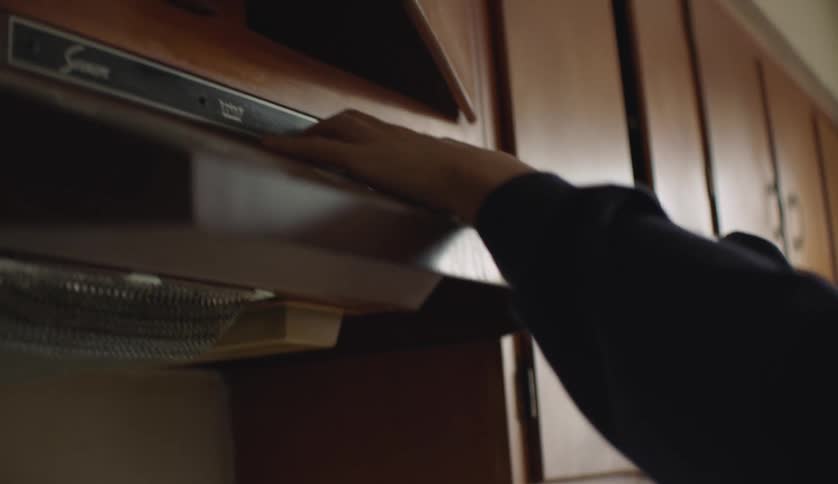 A man struggles to remove the hood from above his stove