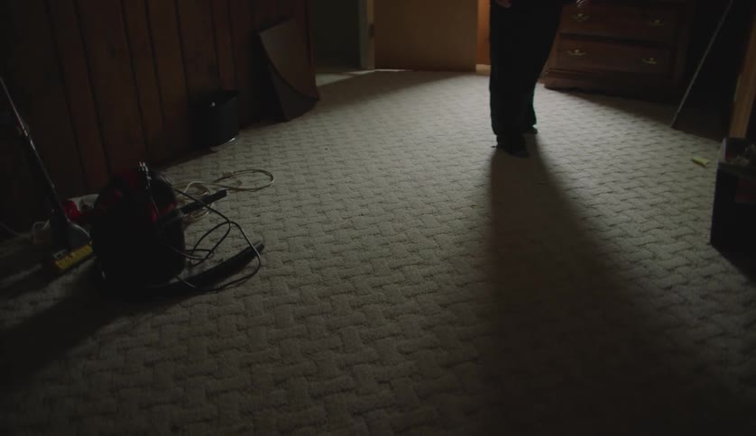 Man walks into a room projecting his shadow on the rug