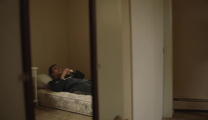 A young teenage boy is laying down on a bed in his bedroom