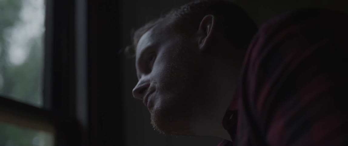 A man drinks from his mug in a dark room