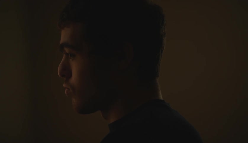 A young white man is standing inside of his room