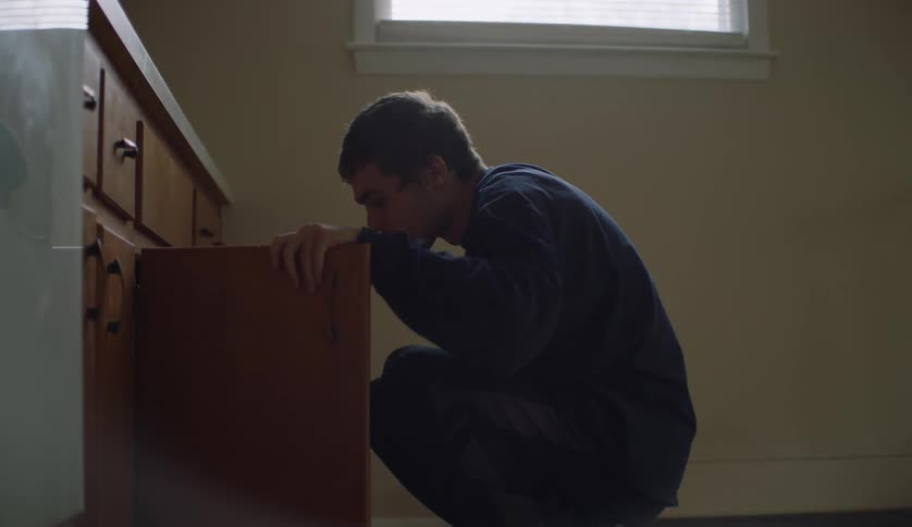A man searches a kitchen cabinet and gets something on his hand