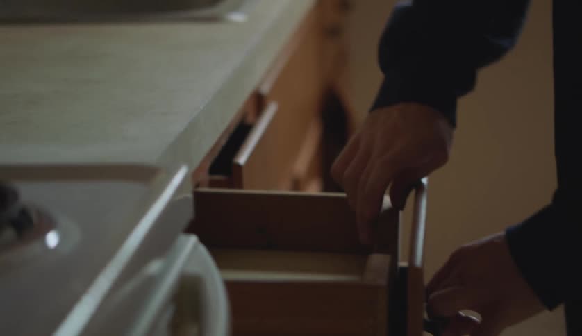 Young man wearching through the empty drawers in the kitchen at home