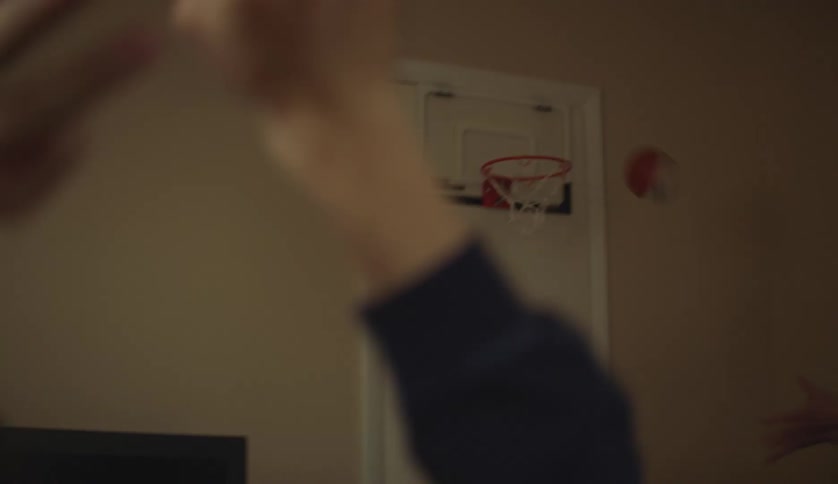 A woman passes a small ball to a man who shoots it at a hoop