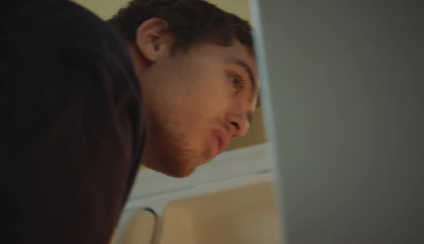 A teenage boy is leaning down looking at the wall in a room