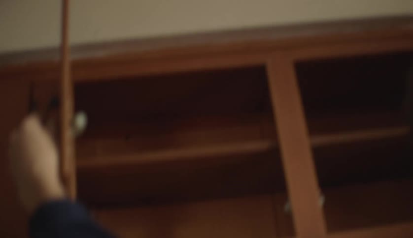 Young man opens the doors of the empty cupboards in the kitchen at home