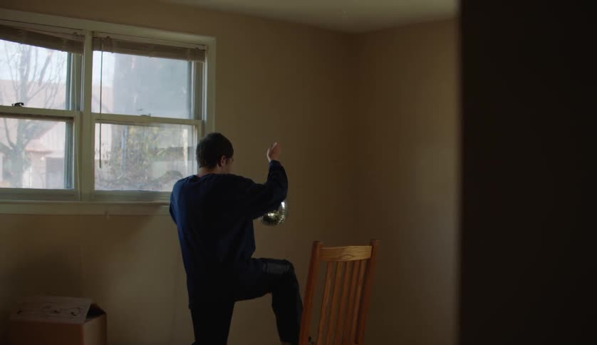 Male carrying chair to corner of room to hang disco ball