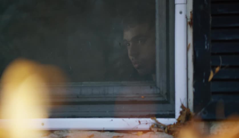 A male is looking out of his window