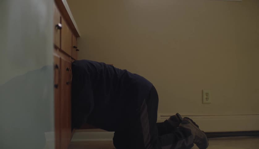 Young man with an intellectual disability searches deep into a cupboard in the kitchen