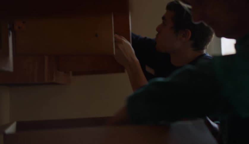 Teenage boy and mother are putting away things into cabinets