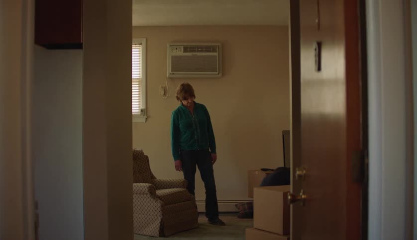 A woman watches her son in a room with unpacked boxes