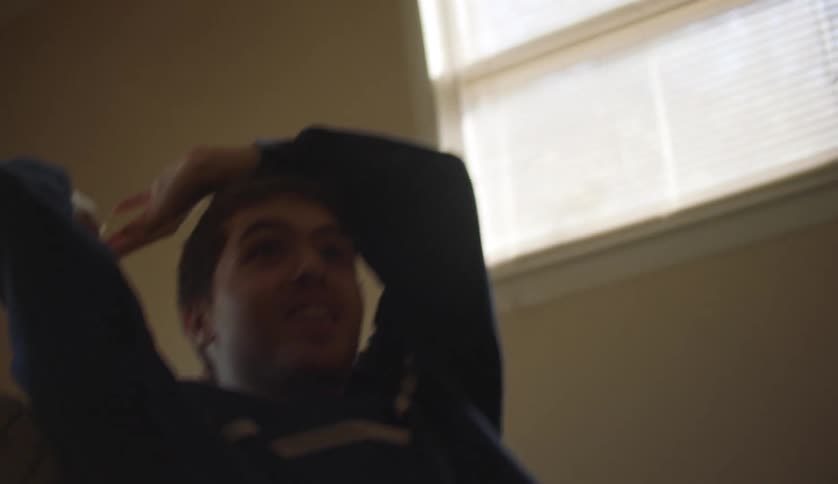 Man sitting in home gestures asking to be thrown ball then catches and throws it in turn