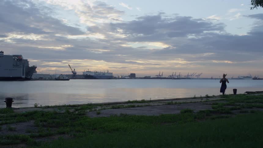 A woman is running by the water at sunset