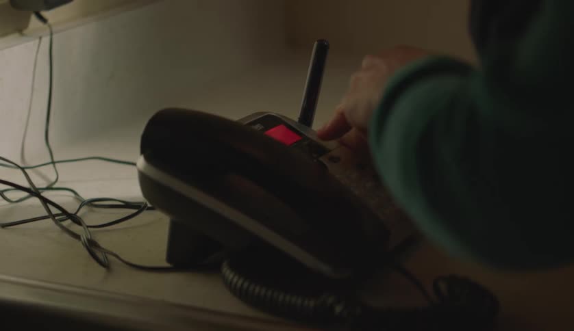 A male is in his kitchen looking at a telephone