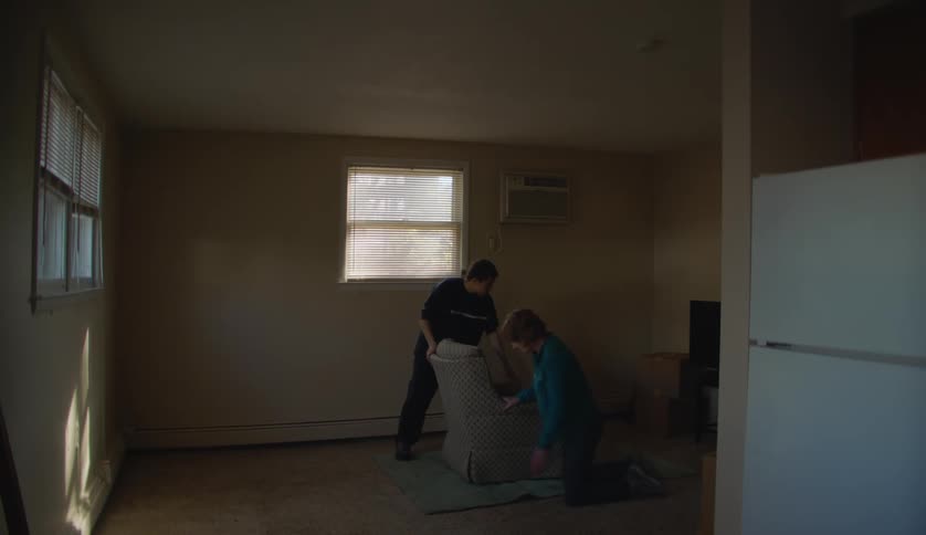 Grandson helps grandmother to put a chair over a rug in the living room