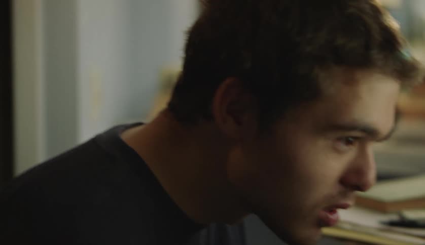 A young man talks while rocking back and forth while playing a computer game