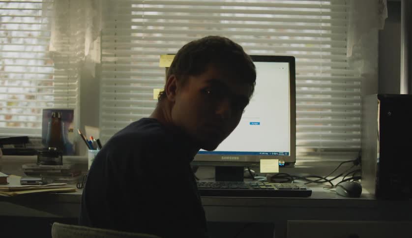 A young teenage boy is sitting down and is using his computer