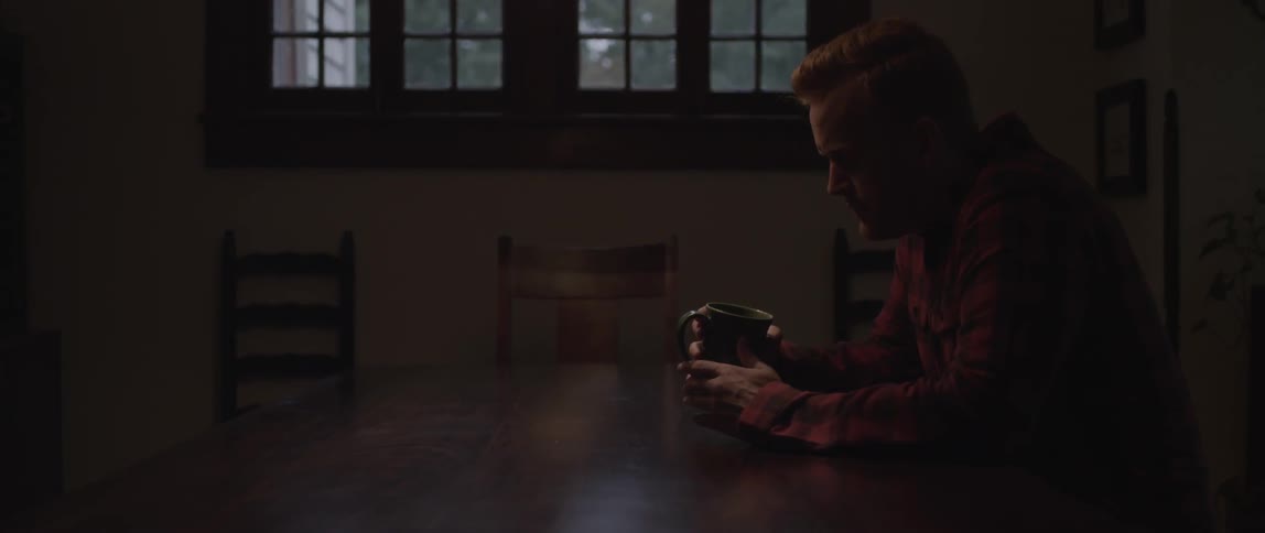 A man in a red shirt drinks from a mug