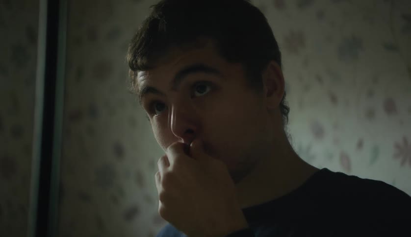 There is a young man inside of his room in the day time