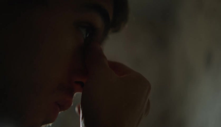 A male is cleaning his face and standing indoors