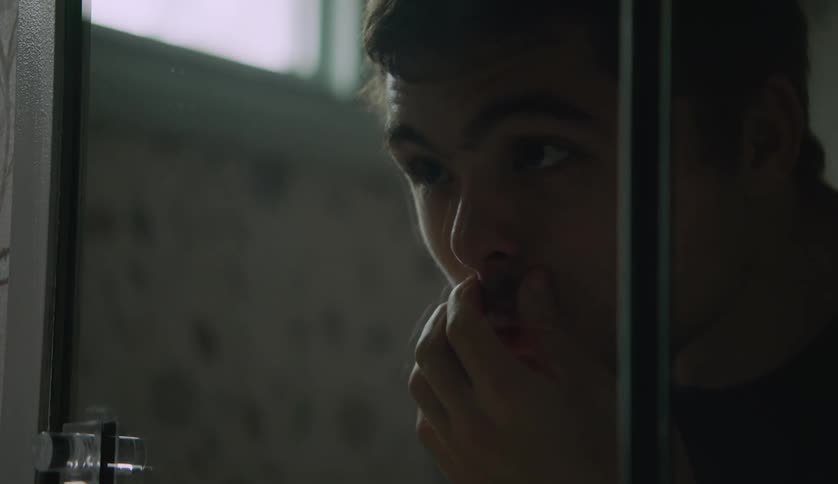Young man with an intellectual disability looking at his face on the mirror in the bathroom
