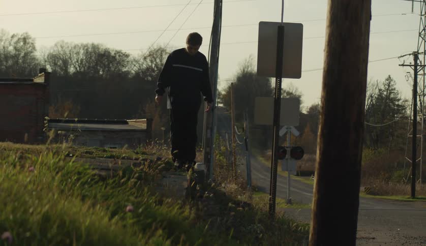 A male is walking in the grass in a small town