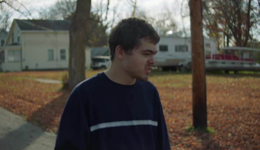 Man with dark blue sweater walks down the street in the countryside