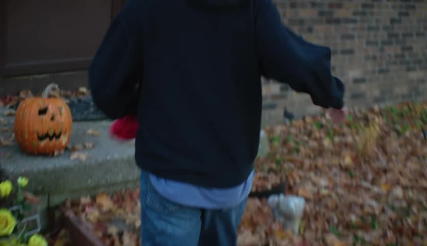 Teenager walks home over the dead leafs on the ground in autumn