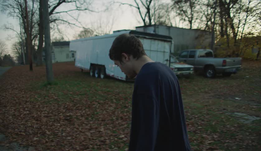 A male is walking through a neighborhood in autumn