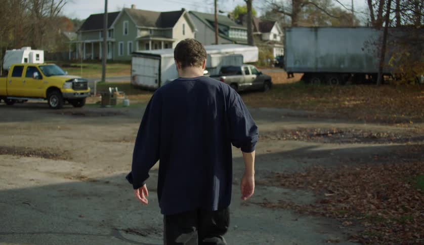 A teenage boy is looking around as he walks on a neighborhood street