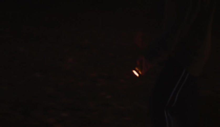 Young man walks out the door with a flashlight pointed to the ground searching for something